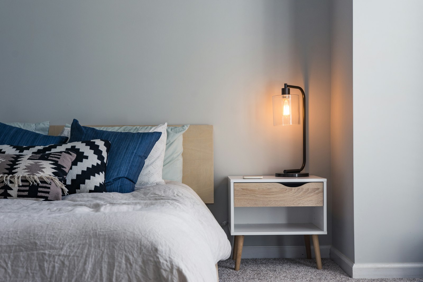 A quiet corner of a bedroom with a warm bedside lamp switched on
