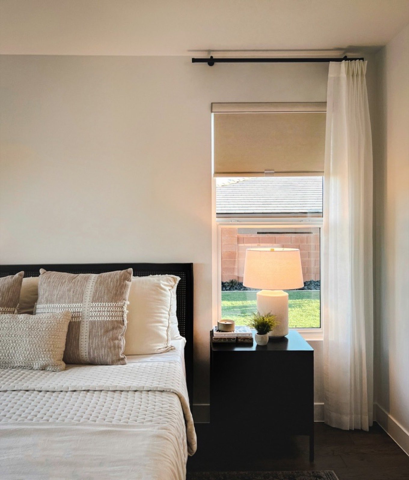 A neutral bedroom with a lit lamp beside a bright window